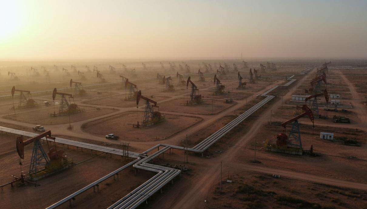 Нефтяное месторождение в Венесуэле на рассвете, работающие нефтяные вышки и трубопроводы на фоне обширного пейзажа.